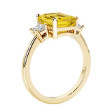 Emerald cut 3 diamond ring representing past, present, and future featuring yellow gemstone center.