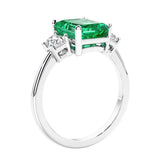 3 stone emerald cut diamond ring in modern gold setting with green gemstone center.
