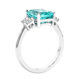 3 stone emerald cut diamond ring in modern gold setting with green gemstone center.