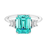 Three stone emerald cut engagement ring for timeless elegance featuring green gemstone and diamonds.