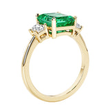 Emerald cut 3 diamond ring representing past, present, and future featuring green gemstone center.
