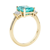 Emerald cut 3 diamond ring representing past, present, and future featuring green gemstone center.
