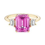 Emerald cut 3 stone engagement ring with pink gemstone and diamond accents.