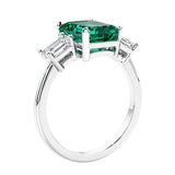 3 stone emerald cut diamond ring in modern gold setting with green gemstone center.