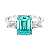 Three stone emerald cut engagement ring for timeless elegance featuring green gemstone and diamonds.
