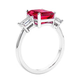 3 stone emerald cut diamond ring in modern gold setting with red gemstone center.