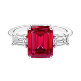 Three stone emerald cut engagement ring for timeless elegance featuring red gemstone and diamonds.