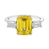 Three stone emerald cut engagement ring for timeless elegance featuring yellow gemstone and diamonds.