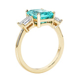 Emerald cut 3 diamond ring representing past, present, and future featuring green gemstone center.