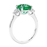 Cushion cut diamond ring with colombian emerald as a unique engagement ring featuring three stone design.