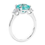 Cushion cut diamond ring with paraiba tourmaline as a unique engagement ring featuring three stone design.