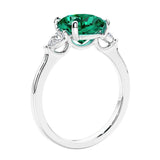 Cushion cut diamond ring as a unique engagement ring featuring three stone design with green emerald and diamonds.