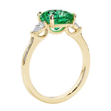 Three stone cushion diamond ring in yellow gold setting with colombian emerald and diamonds.