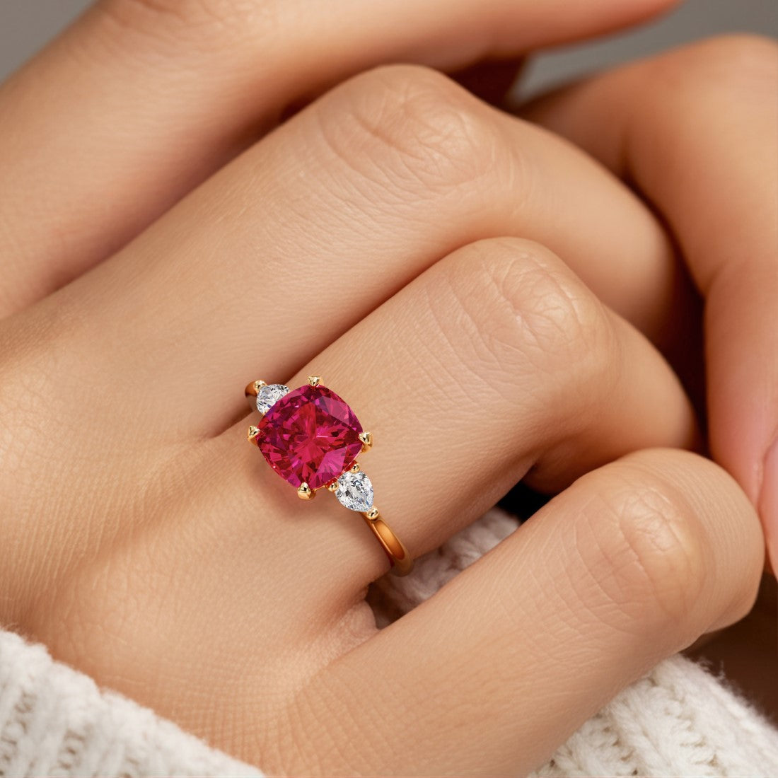 Woman wearing a cushion cut 3 stone ring with romantic styling featuring red ruby and diamonds.