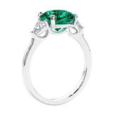 Cushion cut diamond ring as a unique engagement ring featuring three stone design with green emerald and diamonds.