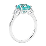 Cushion cut diamond ring as a unique engagement ring featuring three stone design with paraiba tourmaline and diamonds.