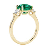 Three stone cushion diamond ring in yellow gold setting with green emerald and diamonds.