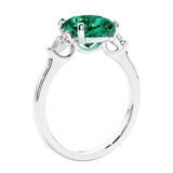 Cushion cut diamond ring as a unique engagement ring featuring three stone design with green gemstone and diamonds.