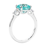 Cushion cut diamond ring as a unique engagement ring featuring three stone design with green gemstone and diamonds.