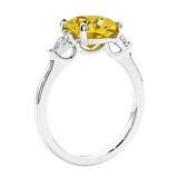 Cushion cut diamond ring as a unique engagement ring featuring three stone design with yellow gemstone and diamonds.