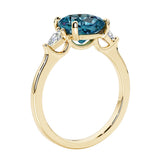 Three stone cushion diamond ring in yellow gold setting with gemstone and diamonds.
