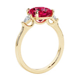 Three stone cushion diamond ring in yellow gold setting with red gemstone and diamonds.