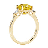 Three stone cushion diamond ring in yellow gold setting with yellow gemstone and diamonds.