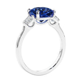 Cushion cut diamond ring as a unique engagement ring featuring three stone design with blue gemstone and diamonds.