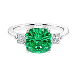 Cushion shaped engagement ring with brilliant diamonds and green gemstone.