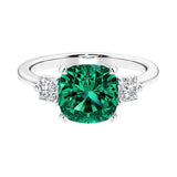 Cushion shaped engagement ring with brilliant diamonds and green gemstone.