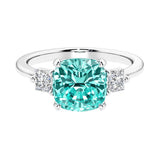 Cushion shaped engagement ring with brilliant diamonds and green gemstone.