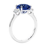 Cushion cut diamond ring as a unique engagement ring featuring three stone design with blue gemstone and diamonds.