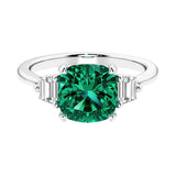 Cushion shaped engagement ring with brilliant diamonds and green gemstone.