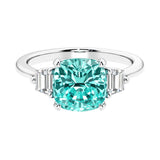 Cushion shaped engagement ring with brilliant diamonds and green gemstone.