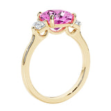 Three stone cushion diamond ring in yellow gold setting with pink gemstone and diamonds.