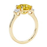 Three stone cushion diamond ring in yellow gold setting with yellow gemstone and diamonds.