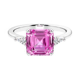 Asscher gemstone diamond ring with step-cut sparkle in a three stone setting featuring pink sapphire center.