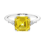 Asscher gemstone diamond ring with step-cut sparkle in a three stone setting featuring yellow sapphire center.