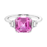 Asscher gemstone diamond ring with step-cut sparkle in a three stone setting featuring pink sapphire center.