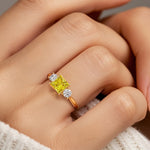 Woman modeling a princess cut three stone engagement ring with yellow sapphire and diamonds.