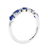 Women’s anniversary ring with lab created blue sapphire and sparkling round diamonds in a vintage-inspired half eternity style.