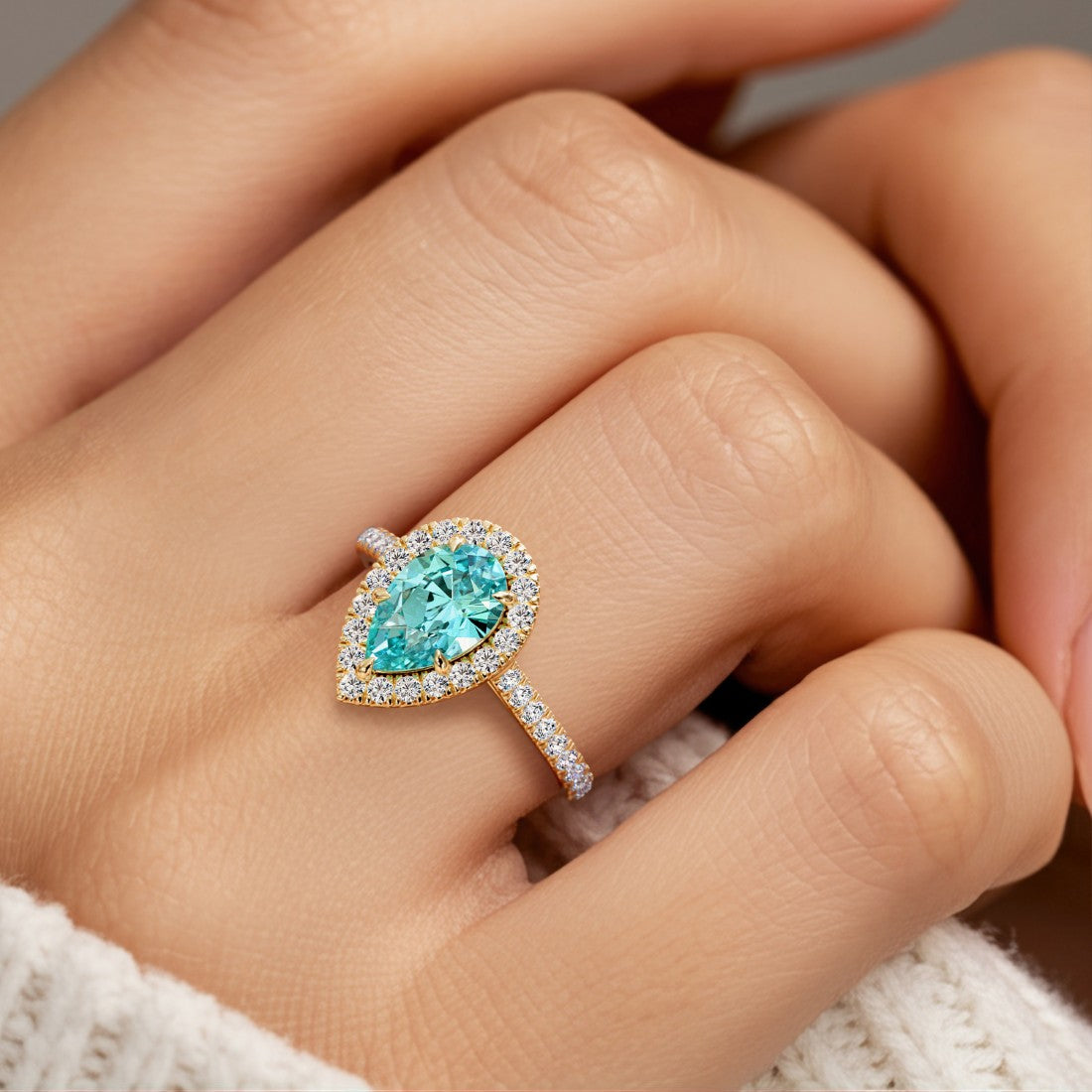 Woman wearing pear shaped alexadrite halo ring with diamonds.