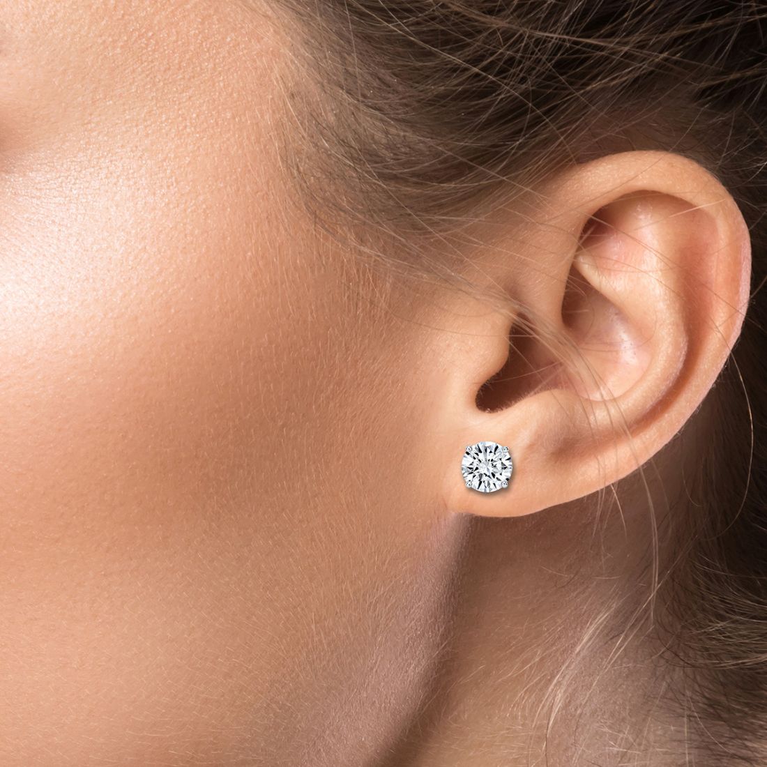 Close-up of an ear wearing a diamond stud earring.