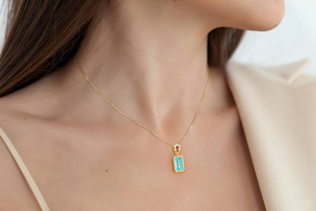 Woman wearing a green paraiba tourmaline necklace with bezel setting by Pel & Co.