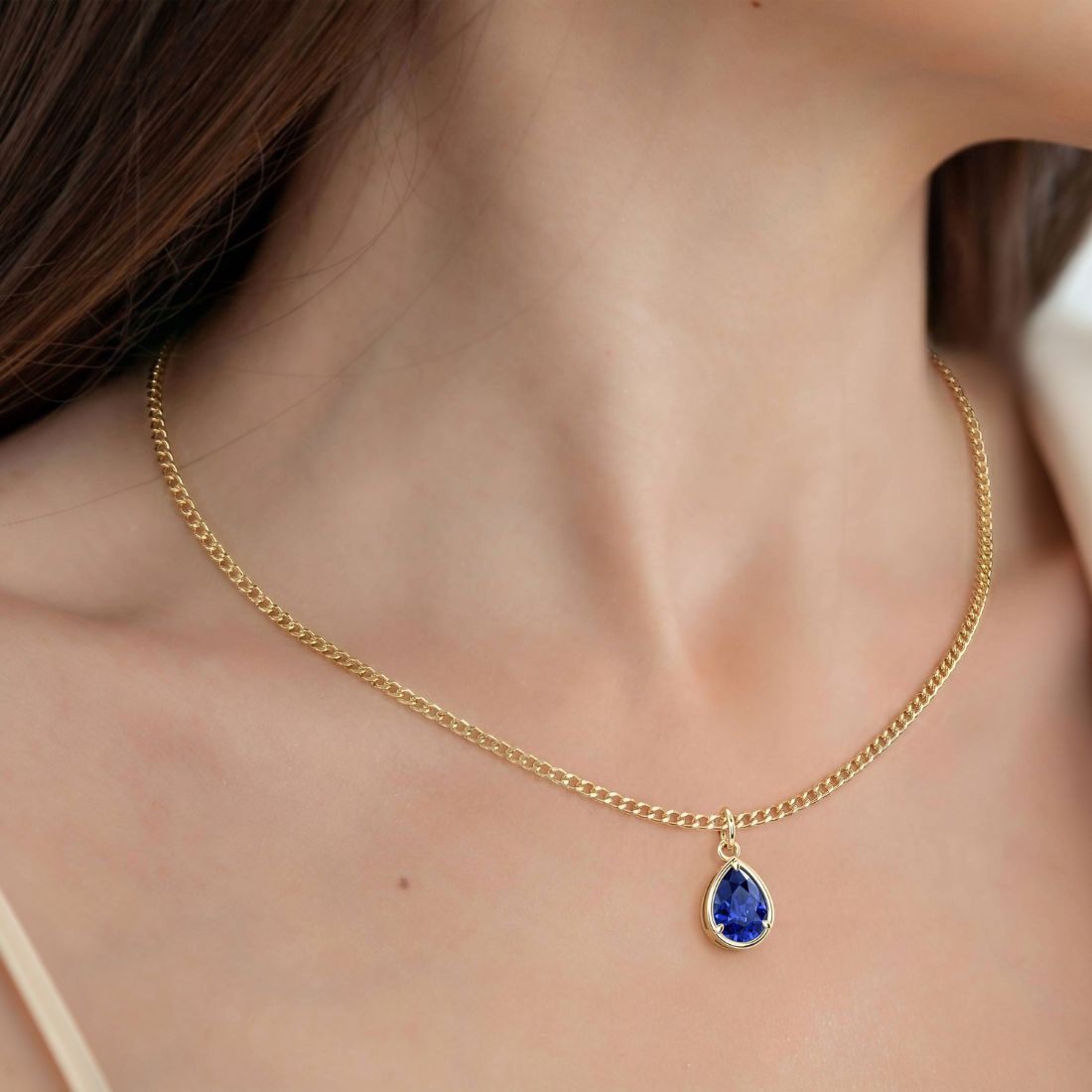 Woman wearing Pear Blue Sapphire Solitaire Pendant Necklace 14x10mm 8 Carat in 14K Gold with Cable Curb Chain