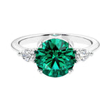 3 stone emerald and diamond engagement ring with round center, symbolizing past, present, and future, set in 14k white gold.