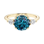 Three stone round engagement ring with a brilliant round alexandrite center diamond and two round side stones.