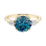 Three stone round engagement ring with a brilliant round alexandrite center diamond and two round side stones.