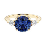 Three stone round engagement ring with a brilliant round blue sapphire center diamond and two round side stones.