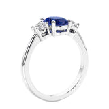 Oval cut three stone blue sapphire and diamond engagement ring with romantic charm.